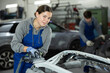 © JackF - At service station, worker is engaged in straightening, eliminating deformations of car body. Auto mechanic at work. Girl auto mechanic polishes body parts by car buffer polisher machine tool