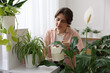 © New Africa - Woman watering beautiful potted houseplant at home