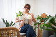 © New Africa - Woman watering beautiful potted houseplant at home