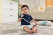 © New Africa - Child safety at home. Little boy playing with extension cord on floor indoors