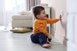 © New Africa - Child safety at home. Little boy taking plug out of power outlet indoors