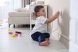 © New Africa - Child safety at home. Little boy taking plug out of power outlet indoors