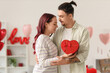 © Pixel-Shot - Young lovely couple with gift hugging at home. Valentine's Day celebration