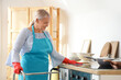 © Pixel-Shot - Mature woman with walker and rag cleaning counter in kitchen