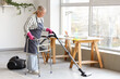 © Pixel-Shot - Mature woman with walker and vacuum cleaner cleaning floor at home