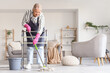 © Pixel-Shot - Mature woman with walker and bucket mopping floor at home