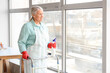 © Pixel-Shot - Mature woman with walker and detergent cleaning window at home
