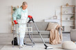 © Pixel-Shot - Mature woman with walker and vacuum cleaner cleaning carpet at home