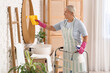 © Pixel-Shot - Mature woman with walker and rag cleaning mirror in bathroom