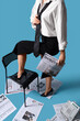 © Pixel-Shot - Young businesswoman in high heels with many newspapers and chair on blue background, top view