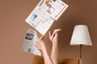 © Pixel-Shot - Legs of woman in high heels with lamp and many newspapers on armchair against brown background