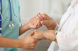 © Pixel-Shot - Female caregiver with senior woman holding hands at home, closeup