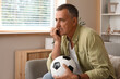 © Pixel-Shot - Worried mature man with soccer ball biting nails while watching TV at home