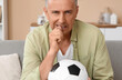 © Pixel-Shot - Worried mature man with soccer ball biting nails while watching TV at home