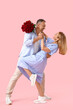 © Pixel-Shot - Happy mature couple with bouquet of roses dancing on pink background. Valentine's Day celebration