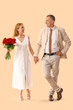 © Pixel-Shot - Happy mature couple with bouquet of roses holding hands on beige background. Valentine's Day celebration