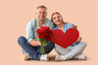 © Pixel-Shot - Happy mature couple with bouquet of roses sitting on beige background. Valentine's Day celebration