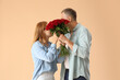 © Pixel-Shot - Happy mature couple with bouquet of roses on beige background. Valentine's Day celebration