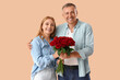 © Pixel-Shot - Happy mature couple with bouquet of roses on beige background. Valentine's Day celebration