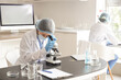 © Pixel-Shot - Female scientist looking through microscope at table in laboratory