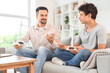 © Pixel-Shot - Teenage boy and his father with wind turbine models sitting on sofa at home