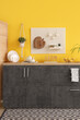 © Pixel-Shot - Interior of stylish kitchen with black counters and peg board near yellow wall