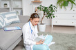 © Pixel-Shot - Young female medical student reading book on floor at home