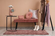 © Pixel-Shot - Cozy bench, rack with clothes and carpet near beige wall in room