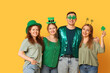 © Pixel-Shot - Group of people with decor hugging on yellow background. St. Patrick's Day celebration