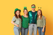© Pixel-Shot - Group of people with decor hugging on yellow background. St. Patrick's Day celebration