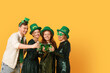 © Pixel-Shot - Group of people with beer on yellow background. St. Patrick's Day celebration