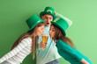 © Pixel-Shot - Young people with beer on green background. St. Patrick's Day celebration