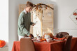 © Pixel-Shot - Beautiful young woman decorating table for Thanksgiving dinner in modern dining room