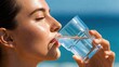 © Gennyson Marinho - A young woman with glowing skin is happily drinking refreshing clear water from a glass under a bright blue sky outdoors.