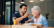 © WesJVR/peopleimages.com - Nurse, man and feeding breakfast with old woman for assisted living, support or nutrition at house. People, caregiver and helping hand with elderly patient, meal and food for diet at nursing home