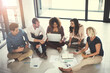 © JamDay/peopleimages.com - Creative, team or meeting with notebook on floor for campaign brief, logo design review or planning. Graphic designers, above or people with discussion at agency for brand guidelines or brainstorming
