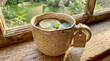 © Lisicus - Steaming mug of herbal tea with lemon slice and fresh mint leaves. Wooden tag labeled mom on handle. Cozy windowsill overlooking lush garden view. Mothers Day gift idea for relaxation and