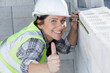 © auremar - happy female builder showing thumb-up while measuring a wall