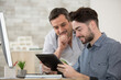 © auremar - two men looking at tablet screen in an office