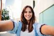 © Jose Calsina - A happy young woman captures a delightful selfie, showcasing her bright smile and engaging personality in a cheerful moment of self-expression and joy.
