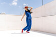 © VISTA by Westend61 - Woman dancing outdoors in blue outfit with red shoes and red hat