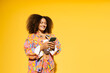 © VISTA by Westend61 - Happy woman with curly hair using smart phone against yellow background