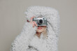 © VISTA by Westend61 - Stylish woman in fur coat taking photo with vintage camera indoors