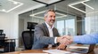 © Muhammad - Smiling Businessman Shaking Hands with Client in Modern Office