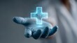 © olga_demina - Human hand in a protective glove holding a glowing, networked medical cross symbol, representing healthcare technology, future medicine, and digital health innovation