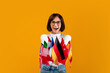© Prostock-studio - Foreign language studying school concept. Excited lady showing bunch of diverse flags, posing and smiling to camera over yellow studio background, free space