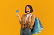 © Prostock-studio - Easy shopping concept. Excited woman holding credit card and shopper bags, carrying purchases, got cashback bonus and looking at camera with open mouth, posing over yellow background