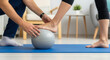 © Iryna - Physiotherapist assisting foot exercise with therapy ball, rehabilitation and balance training in home session
