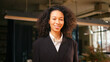 © RZ Images - Beautiful hispanic woman with curly hair in formal wear looking at camera posing in modern office