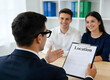 © Paul Alice - Agent immobilier présentant un contrat de location à un jeune couple souriant dans un bureau moderne